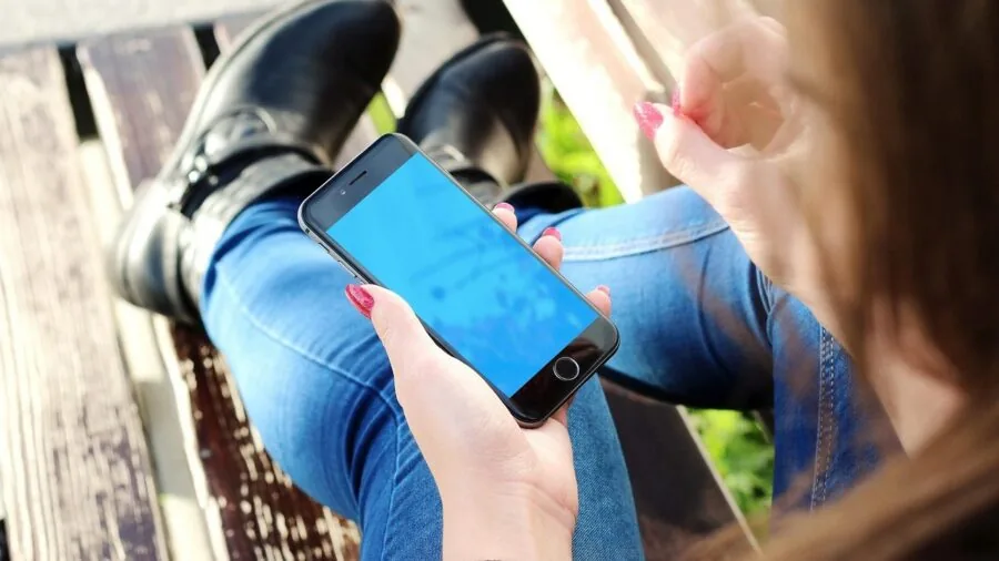 Person charging handheld device while relaxing outside in natural daylight