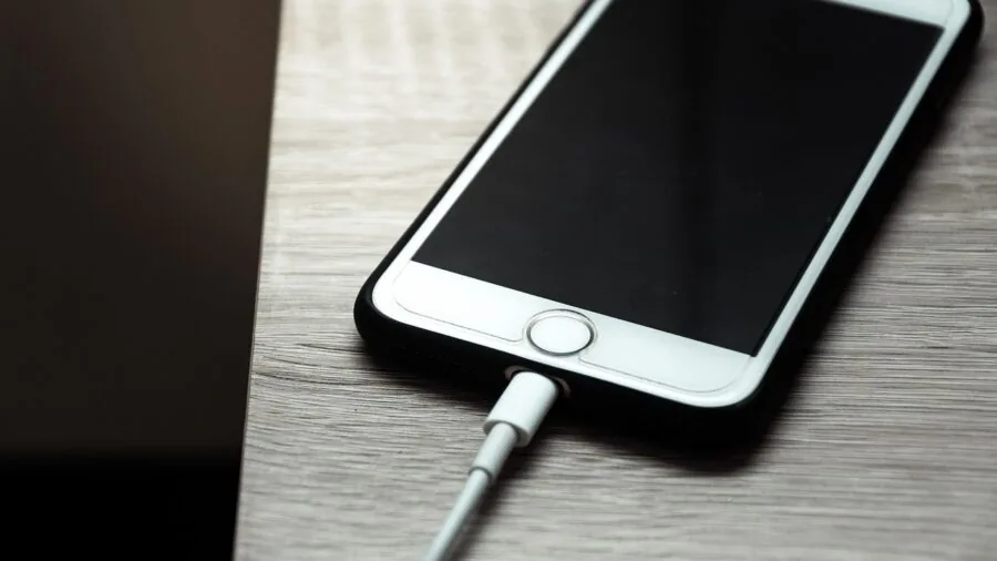 Person charging wireless device with glasses on table, showing daily tech routine and battery management