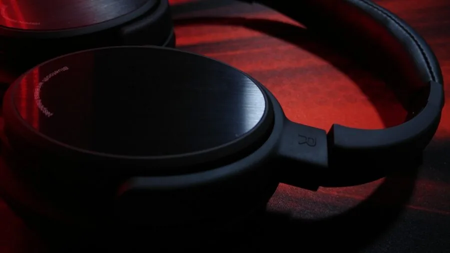 Person charging wireless headphones at home desk with charging cable and power adapter