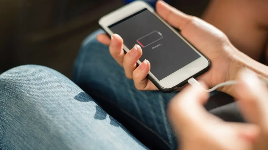 Person checking phone battery life while outdoors, representing portable device charging and power management in real-world use