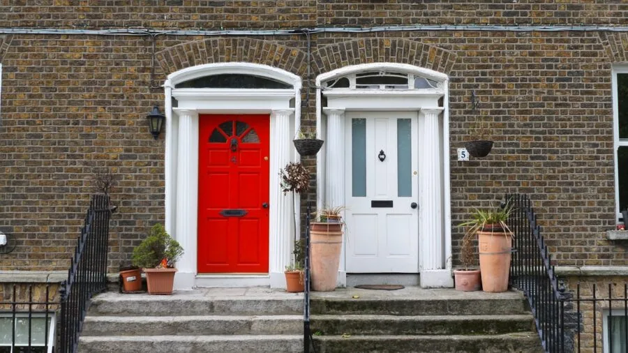 Person checking smart home security system battery indicator on modern front door entry