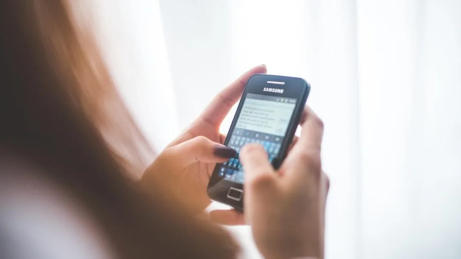 Person checking smartphone updates while sitting outside in natural daylight