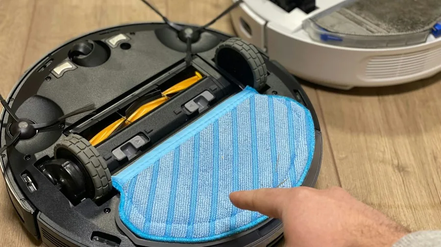 person cleaning robot vacuum brush wheel