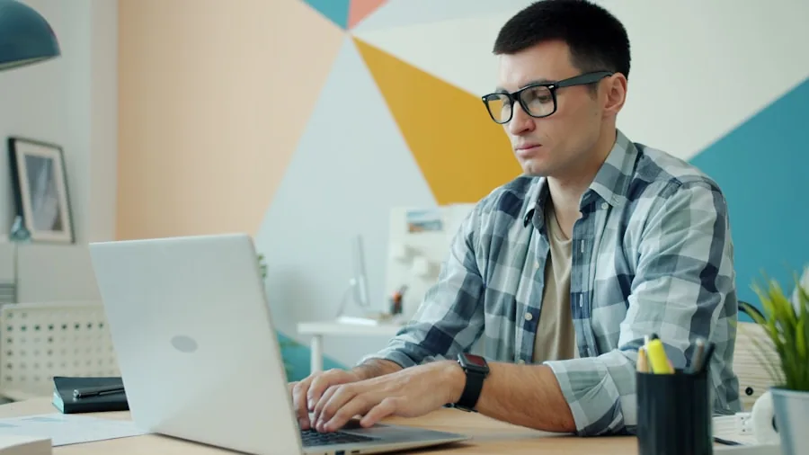 Person concentrating while working on laptop at a desk with documents and coffee