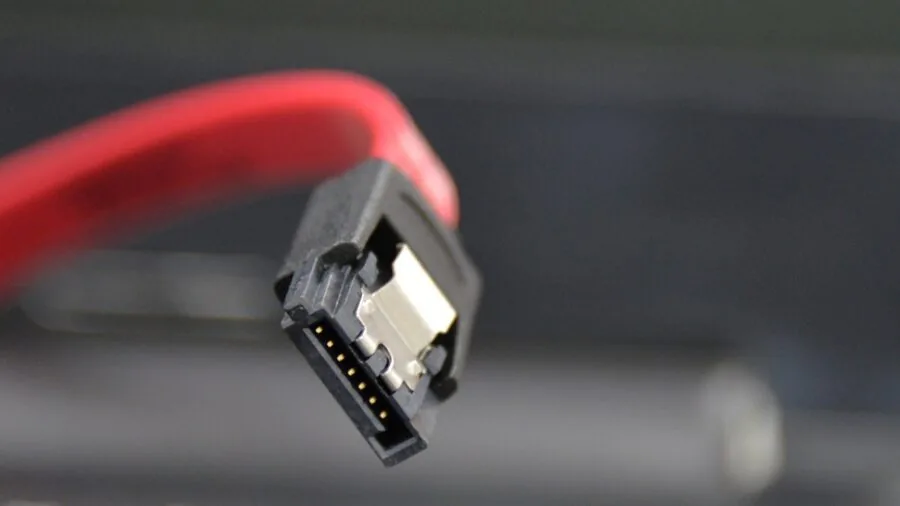 Person connecting cables to back of computer monitor setup, showing connectivity and cable management in home office