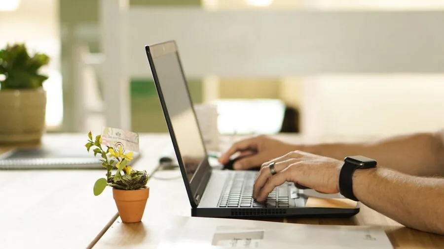Person connecting cables to desktop monitor setup at organized workspace