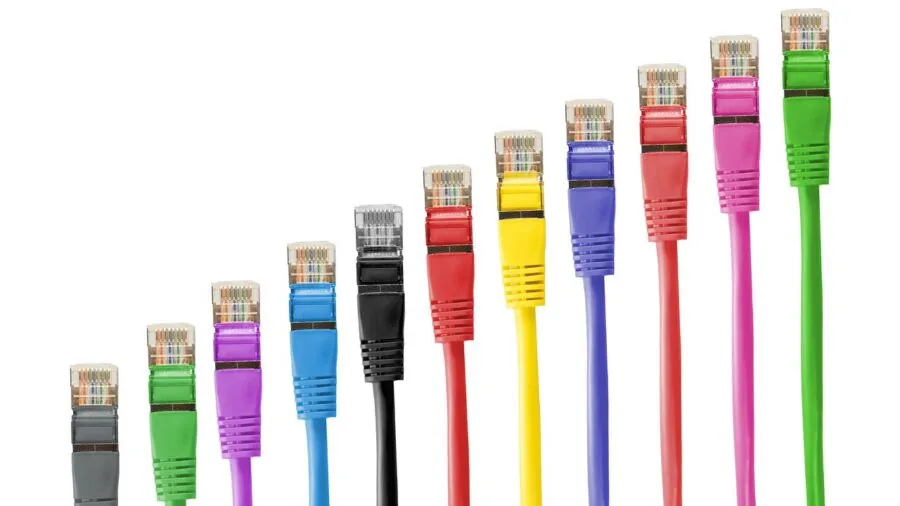 Person connecting ethernet cables to network equipment in home office setup