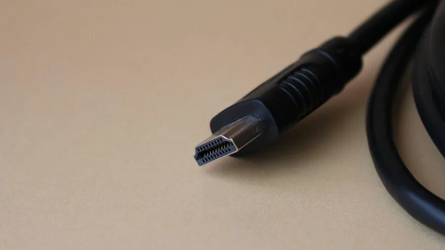 Person connecting HDMI cables to home entertainment system with multiple devices and cables visible