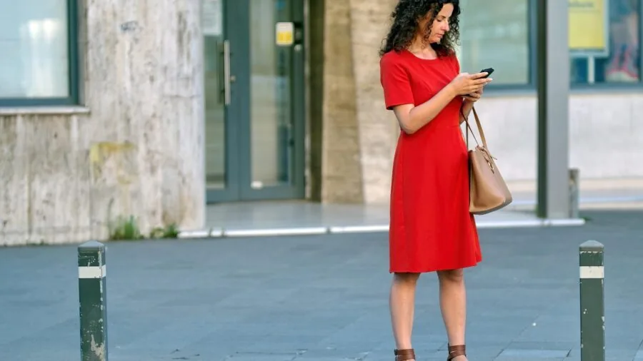 Person customizing audio app settings on smartphone while wearing wireless headphones