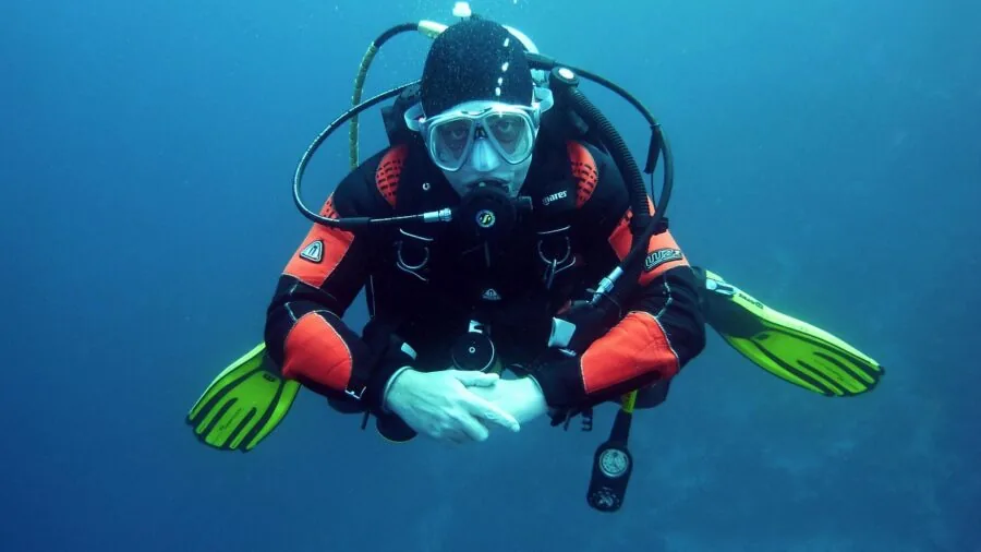 Person diving underwater in clear blue water exploring marine environment with snorkel gear