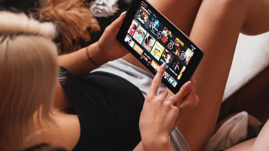 Person enjoying a movie on tablet device with focused attention on the vibrant display screen