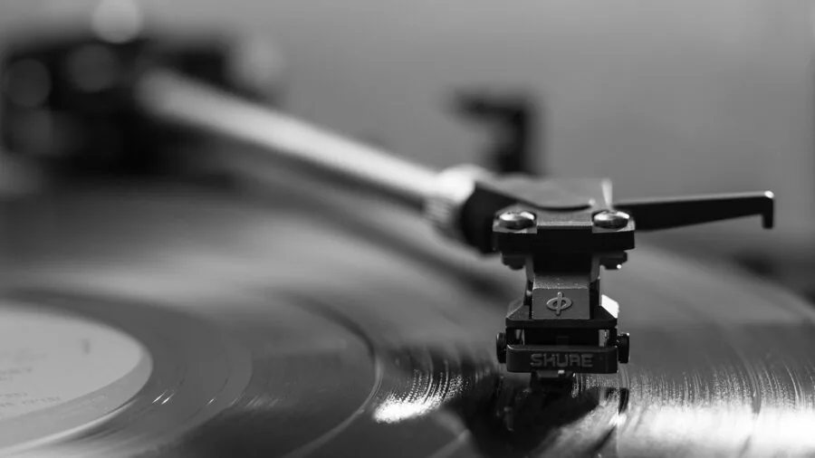 Person enjoying music from vinyl records on turntable in cozy home listening space