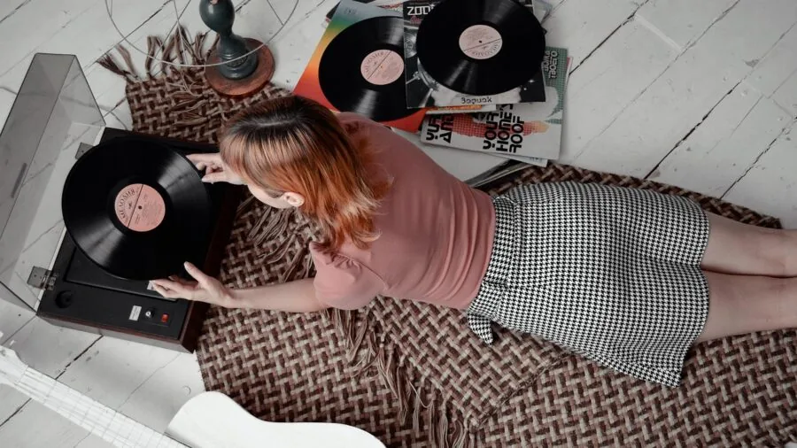 Person enjoying music on turntable in cozy home setting with warm lighting