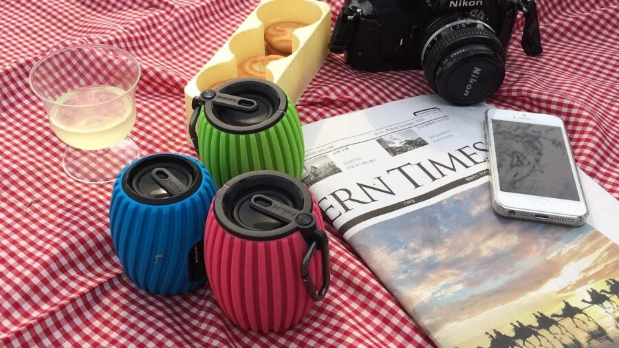 Person enjoying music outdoors with portable speaker during daytime activity