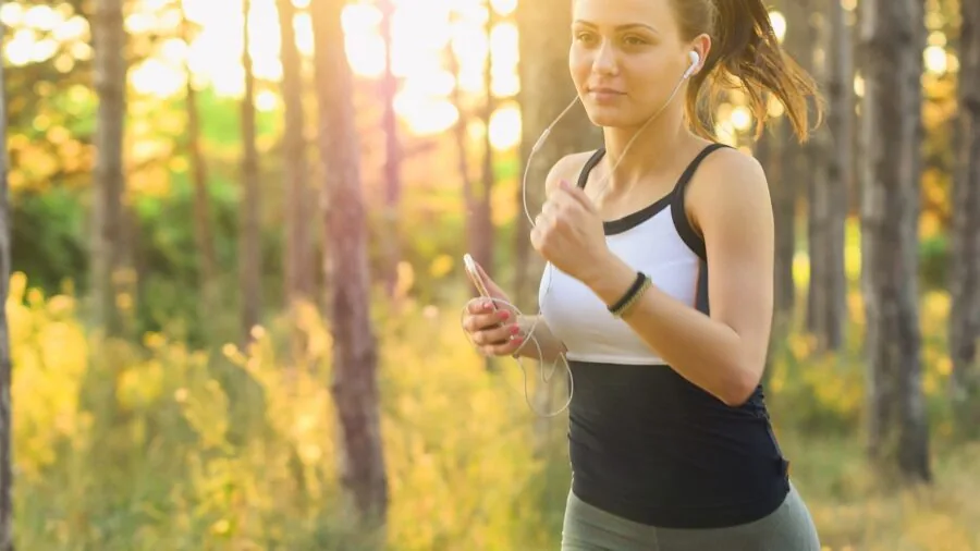 Person enjoying music while exercising outdoors in natural daylight