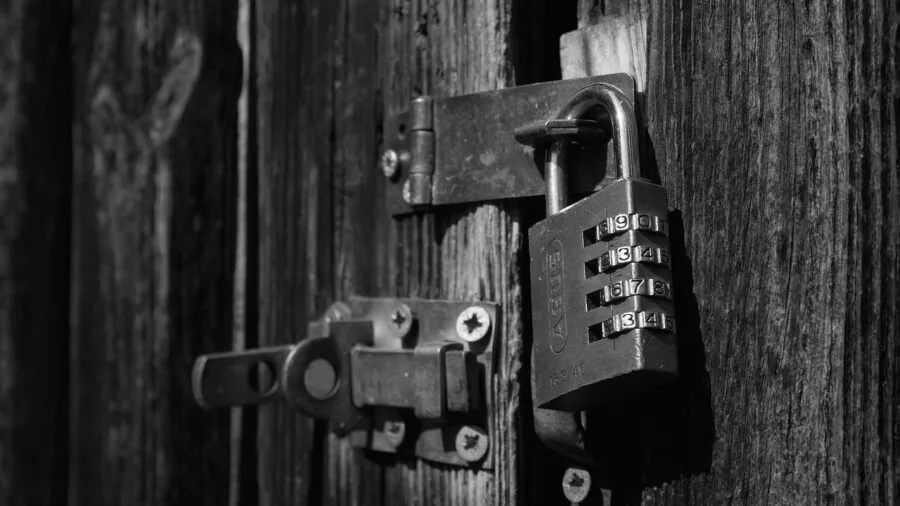 Person entering numeric code on keypad door lock at home entrance