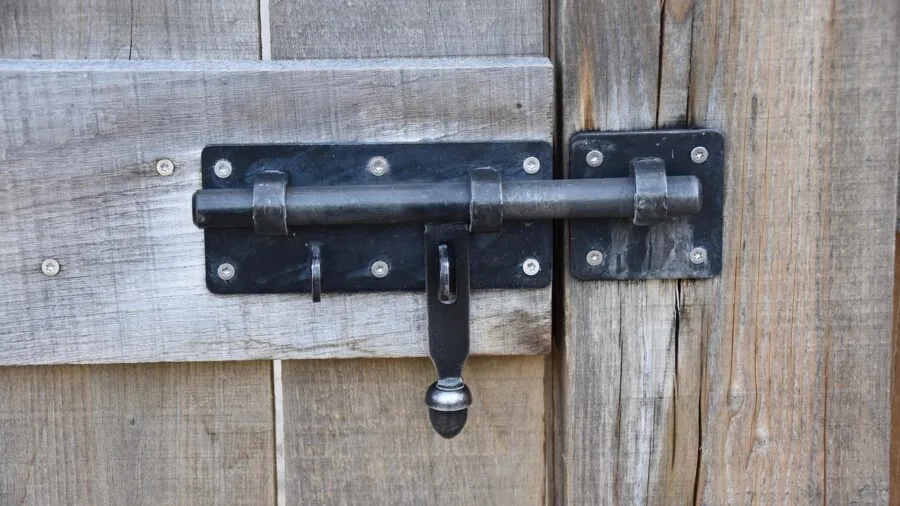 Person examining a smart lock on a residential door, checking battery status and power management