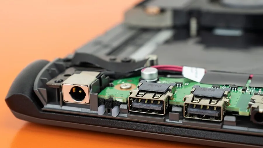 Person examining laptop ports and cables at desk workspace