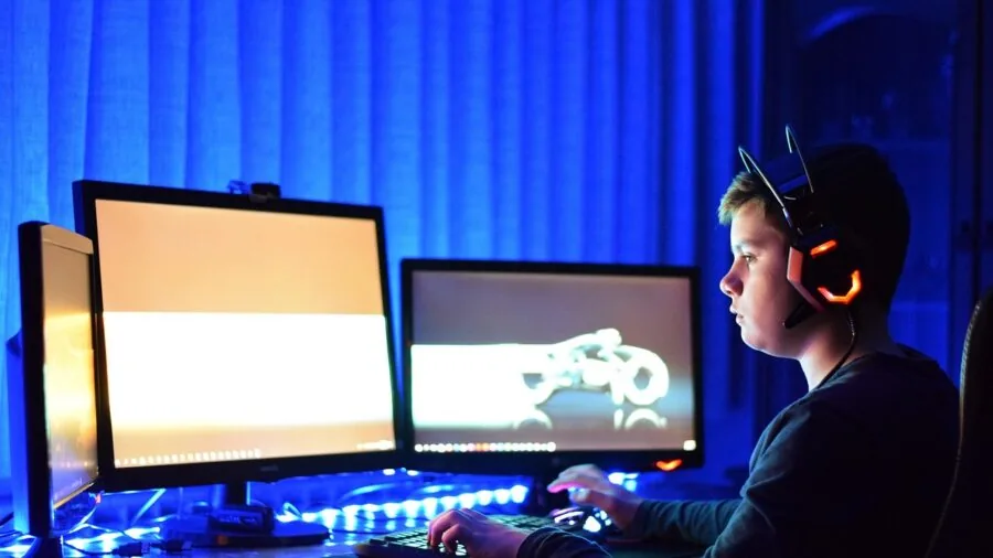 Person gaming at desktop monitor, focused on screen during intense gameplay session
