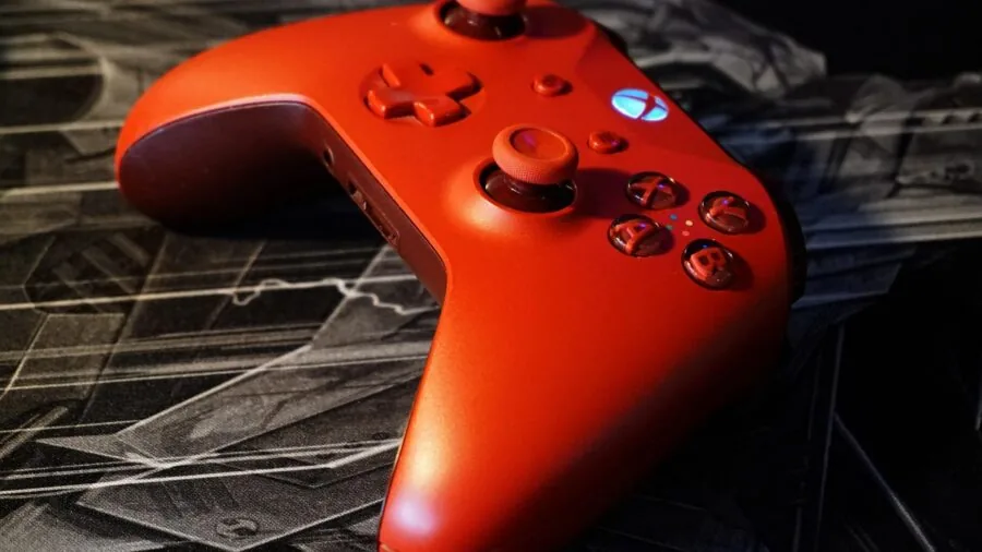 Person gaming on PC with console controllers nearby, showing multi-platform gaming setup