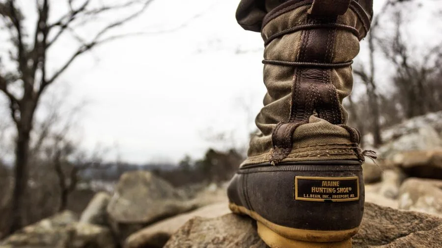 Person hiking through rain and rocky terrain in challenging outdoor conditions