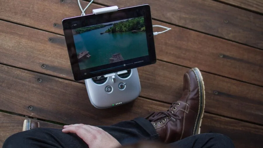 Person holding and using a tablet while sitting outdoors in natural daylight, demonstrating everyday tablet use