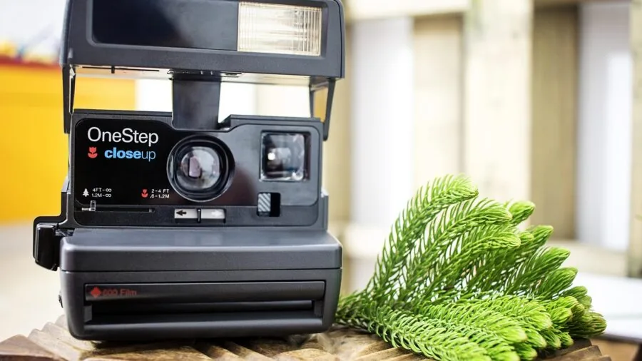 Person holding and viewing instant film prints with white borders, casual lifestyle moment