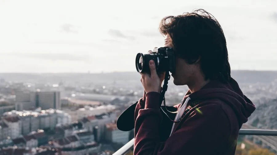 Person holding compact camera while walking through urban street, casual photography lifestyle