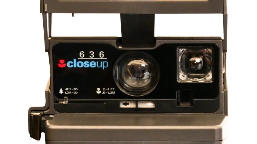 Person holding instant camera capturing a landscape photo in natural daylight