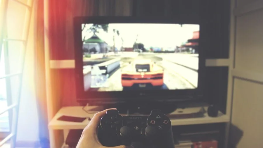 Person holding multiple gaming controllers while playing video games on different platforms