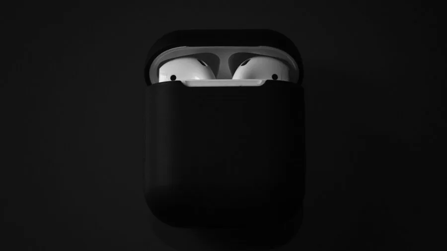 Person holding open charging case with wireless earbuds, lifestyle moment showing battery management and device care