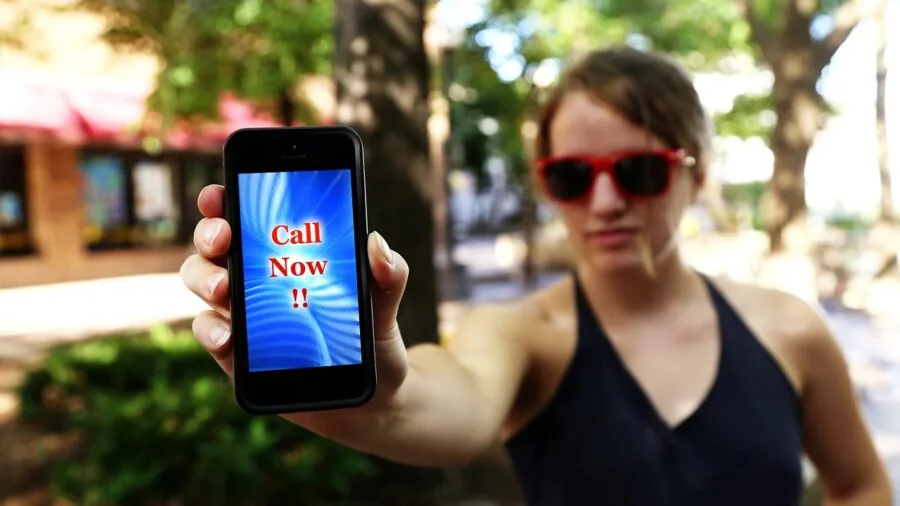 Person holding smartphone connecting to portable audio device via USB cable in casual setting