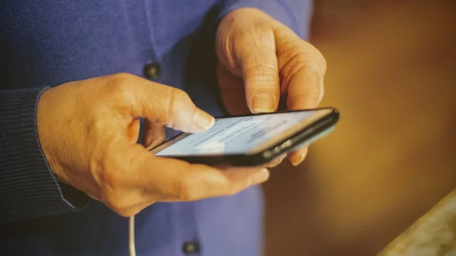 Person holding smartphone while charging with cable, modern lifestyle scene
