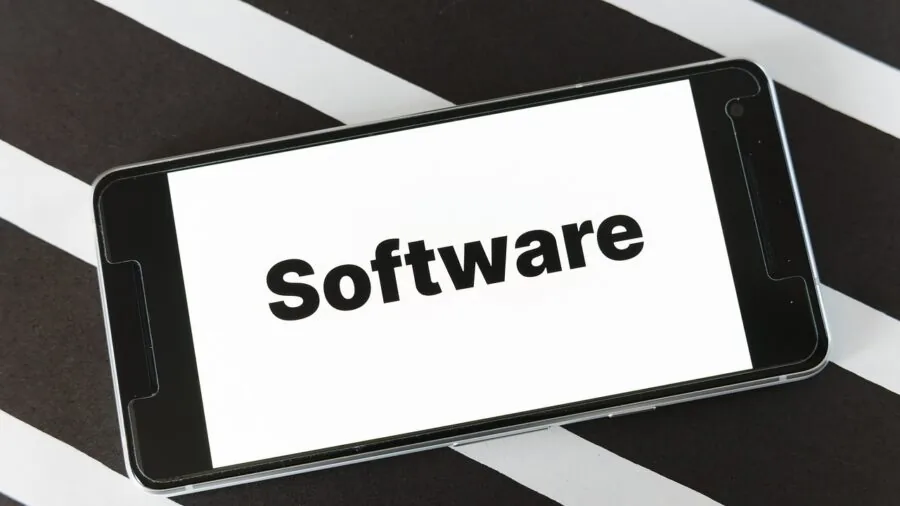 Person holding smartphone while reviewing system software updates on screen in natural lighting