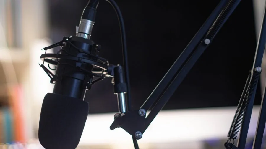 Person in home studio recording podcast with microphone and headphones