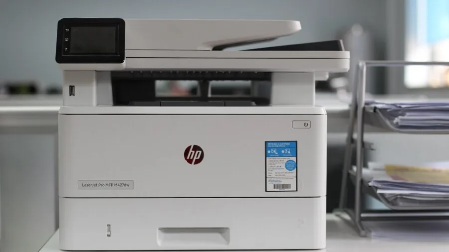 Person inserting paper into home printer tray during office work