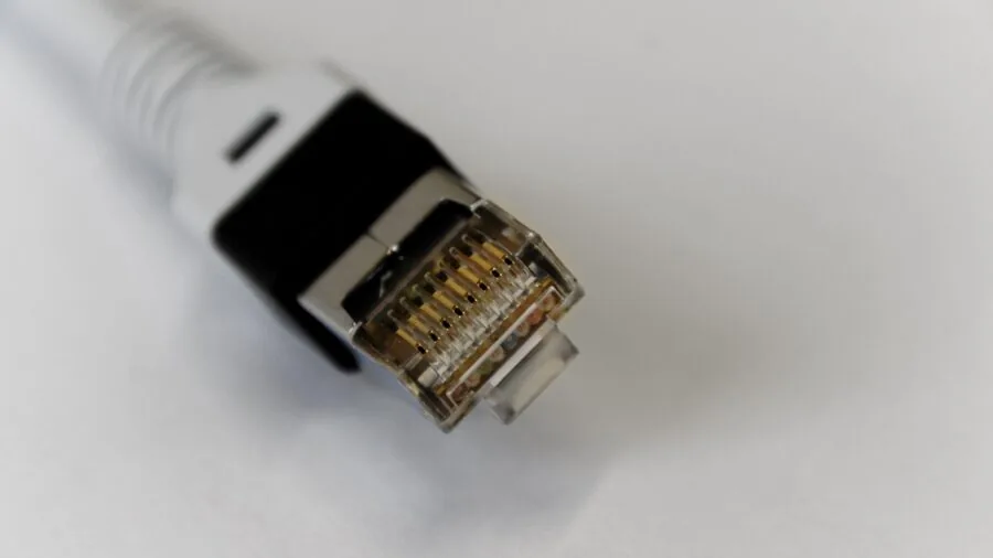 Person inspecting network cables and connections on computer equipment in home office setup