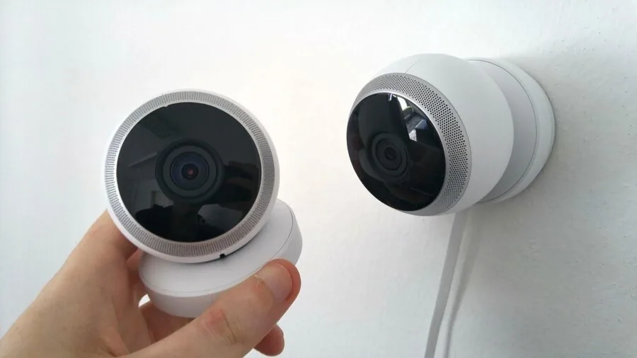 Person installing wireless security camera on residential home exterior wall
