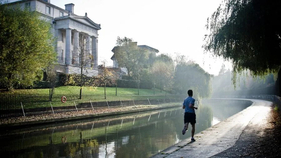 Person jogging outdoors on sunny day with energetic expression, representing active running lifestyle