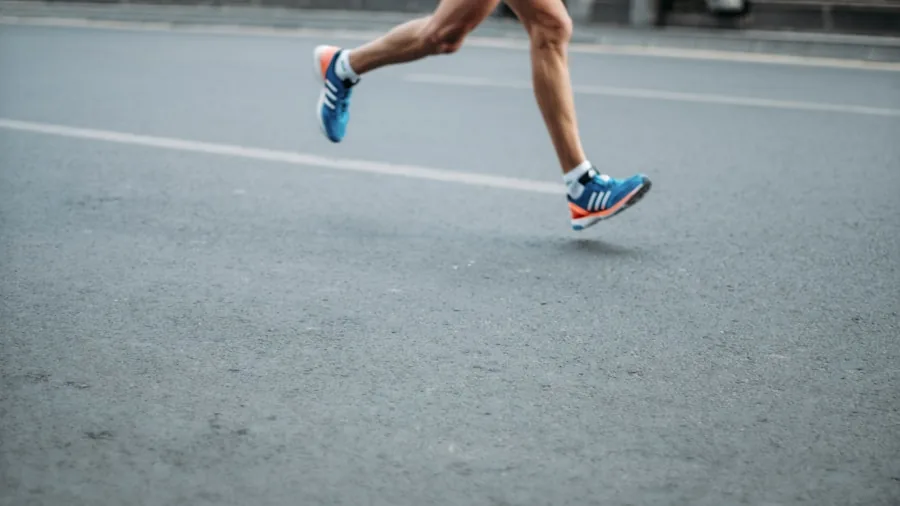 Person jogging outdoors with determined expression during intense workout session