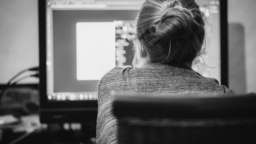 Person leaning in to closely inspect a laptop display screen in natural lighting