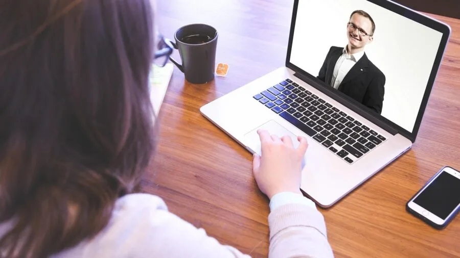 Person on professional video call at home desk with focused lighting and neutral background