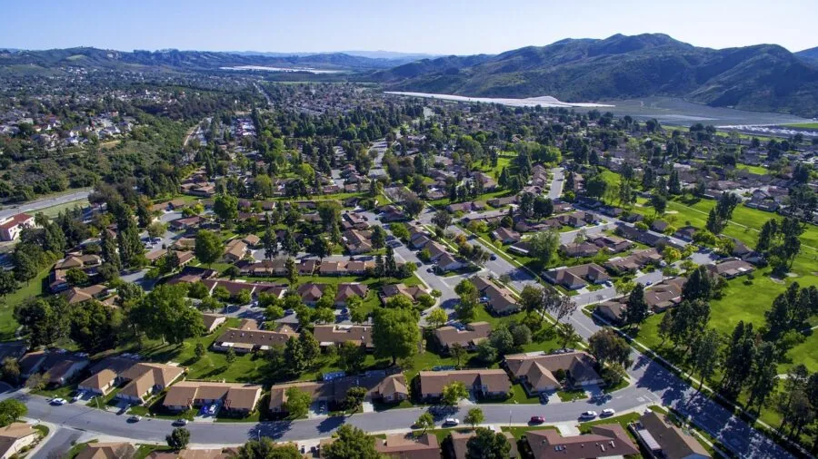Person operating drone in residential suburban area with houses and trees in background