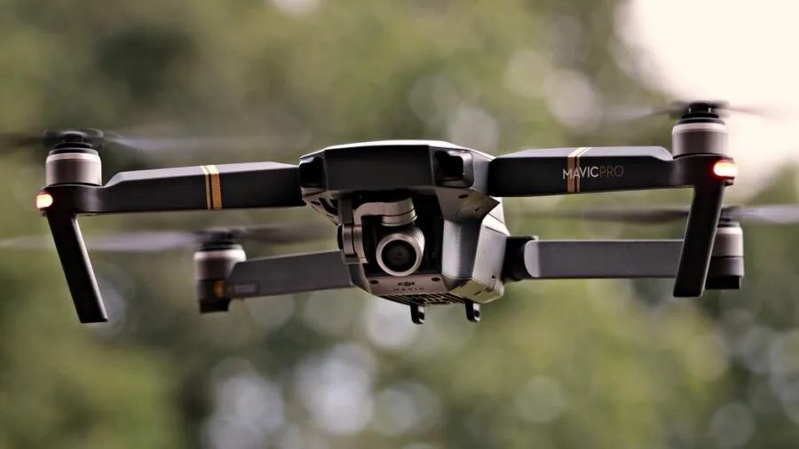 Person operating drone safely near trees and buildings in outdoor environment