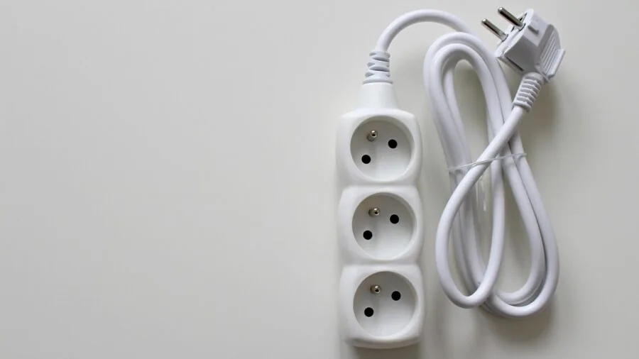 Person organizing cables and power management behind a gaming computer desk setup