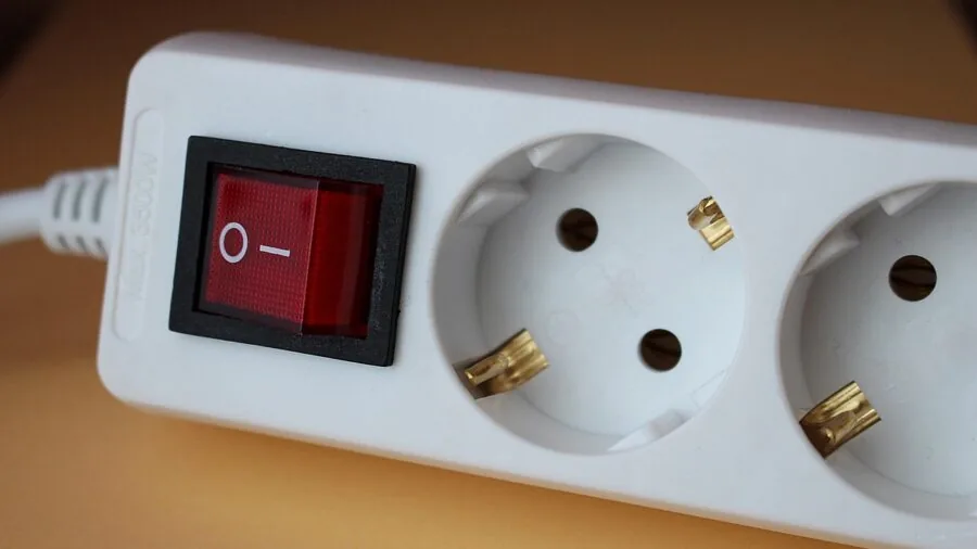 Person organizing electrical outlets and cables on wall behind home office desk setup