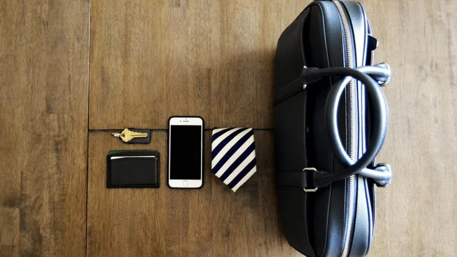 Person organizing everyday carry items including keys and wallet on wooden surface