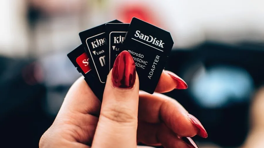 Person organizing multiple microSD memory cards on wooden surface for portable gaming device storage