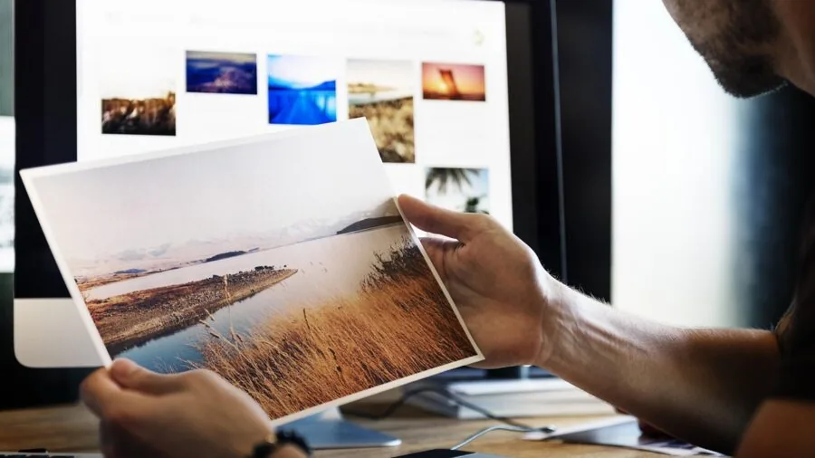 Person organizing photo prints and supplies at a work desk