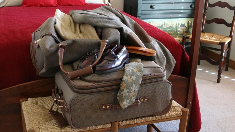 Person organizing travel essentials and headphones into a compact carry-on bag for a flight